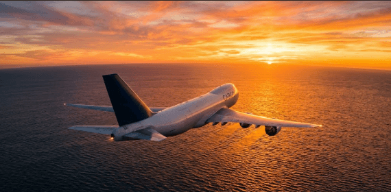 Cargo aircraft flying over ocean at golden hour